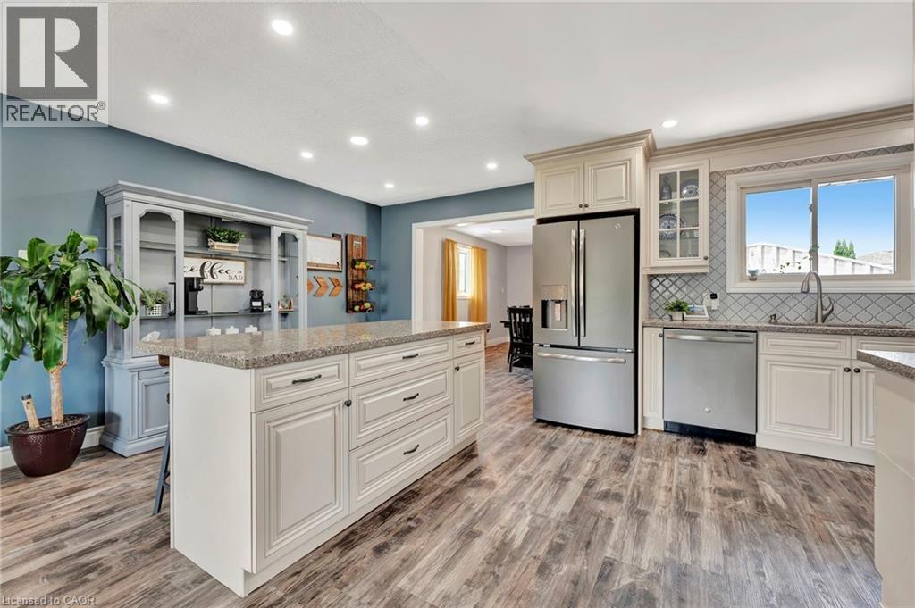 Kitchen featuring a central island with storage, recessed lighting, wood-finish flooring, stainless steel appliances, and a tiled backsplash - 192 Myers Road, Cambridge, ON