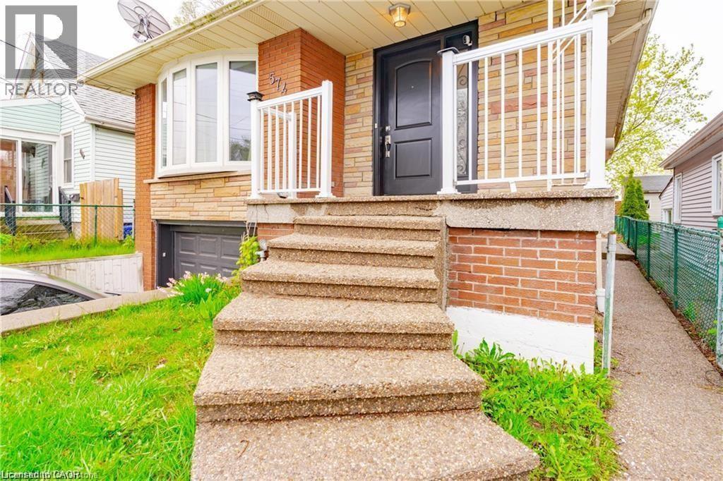 Brick exterior featuring a bay window and an attached garage with a dark gray door - 574 Upper Sherman Avenue, Hamilton, ON