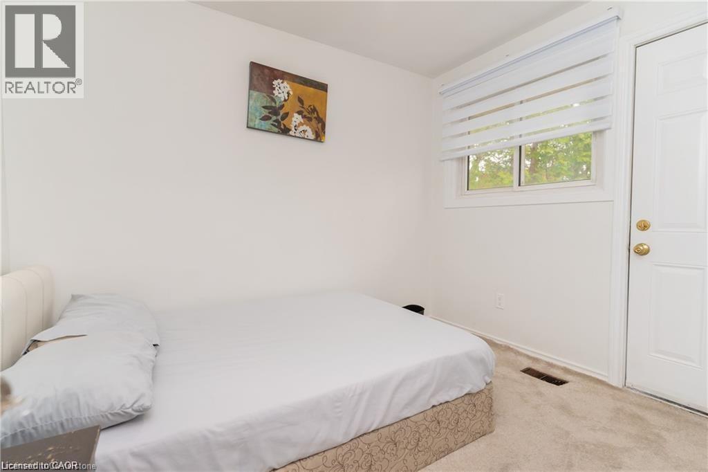 Bright room featuring a white paneled door, a window with horizontal blinds, and neutral-toned carpeting - 574 Upper Sherman Avenue, Hamilton, ON