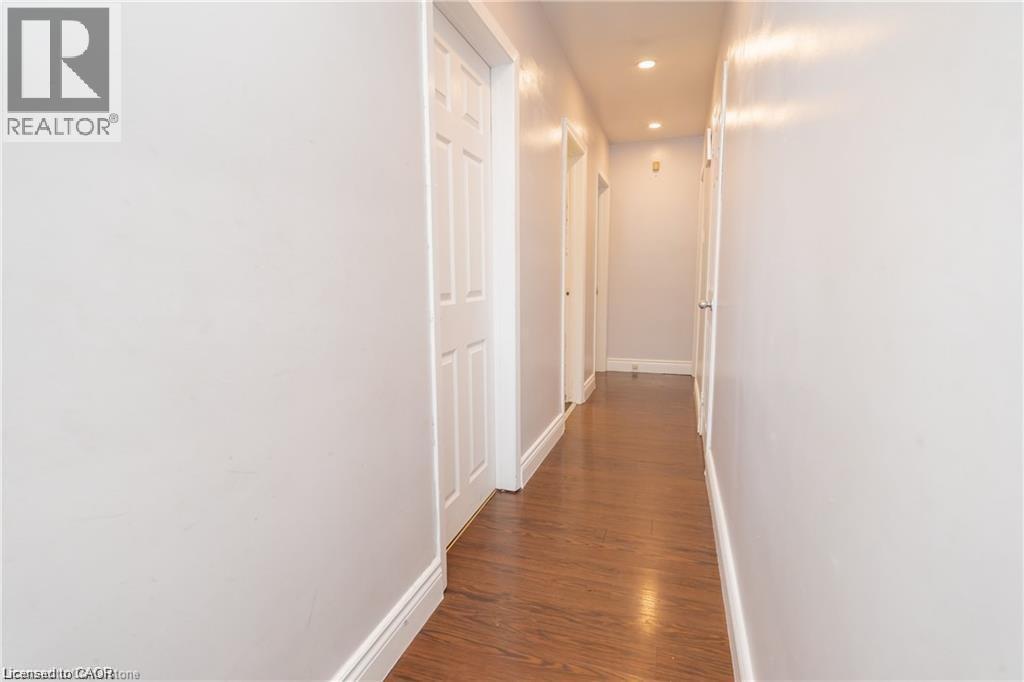 Hallway featuring wood-finish flooring, white baseboards, recessed lighting, and multiple paneled doors - 574 Upper Sherman Avenue, Hamilton, ON