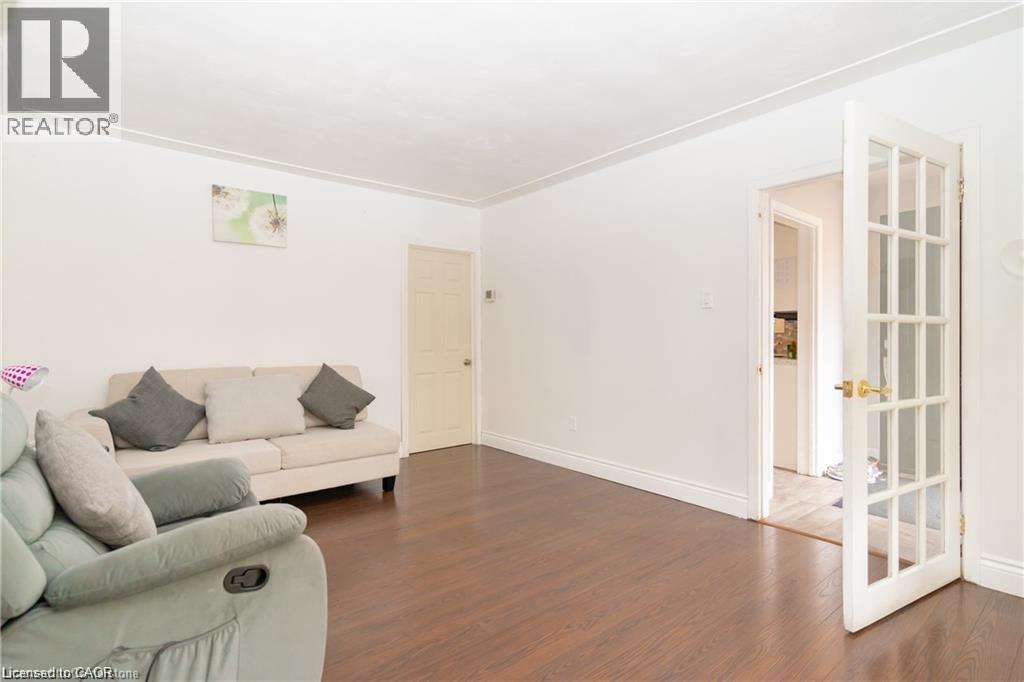 Spacious room featuring wood-finish flooring, white walls, and a white crown molding detail - 574 Upper Sherman Avenue, Hamilton, ON