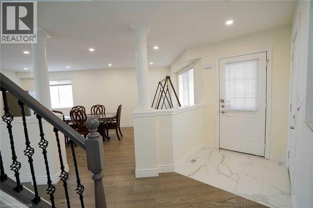 Foyer featuring large format white tile flooring with grey veining, a white entry door with integrated blinds, and an adjacent half-wall - 187 Adler Drive, Cambridge, ON - Indoor Photo Showing Other Room