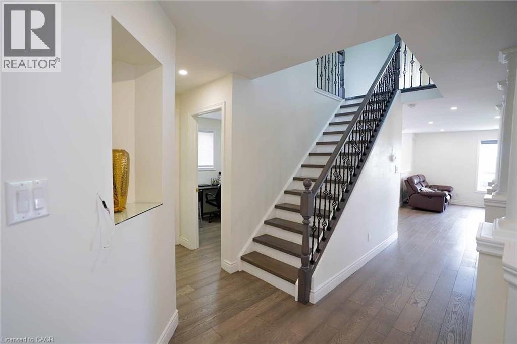Open foyer featuring a custom staircase with dark wood-finish treads and wrought iron spindles - 187 Adler Drive, Cambridge, ON - Indoor Photo Showing Other Room