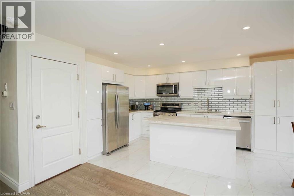 Modern kitchen featuring white gloss cabinetry, stainless steel appliances, a center island with a light-toned countertop, a subway tile backsplash, and recessed lighting - 187 Adler Drive, Cambridge, ON - Indoor Photo Showing Kitchen With Upgraded Kitchen