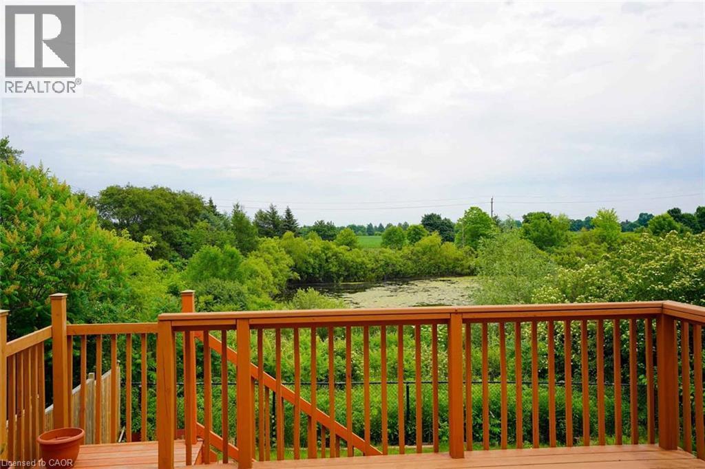 Expansive wood deck with natural wood railing, offering broad views of surrounding verdant trees and a pond - 187 Adler Drive, Cambridge, ON - Outdoor With Deck Patio Veranda With View