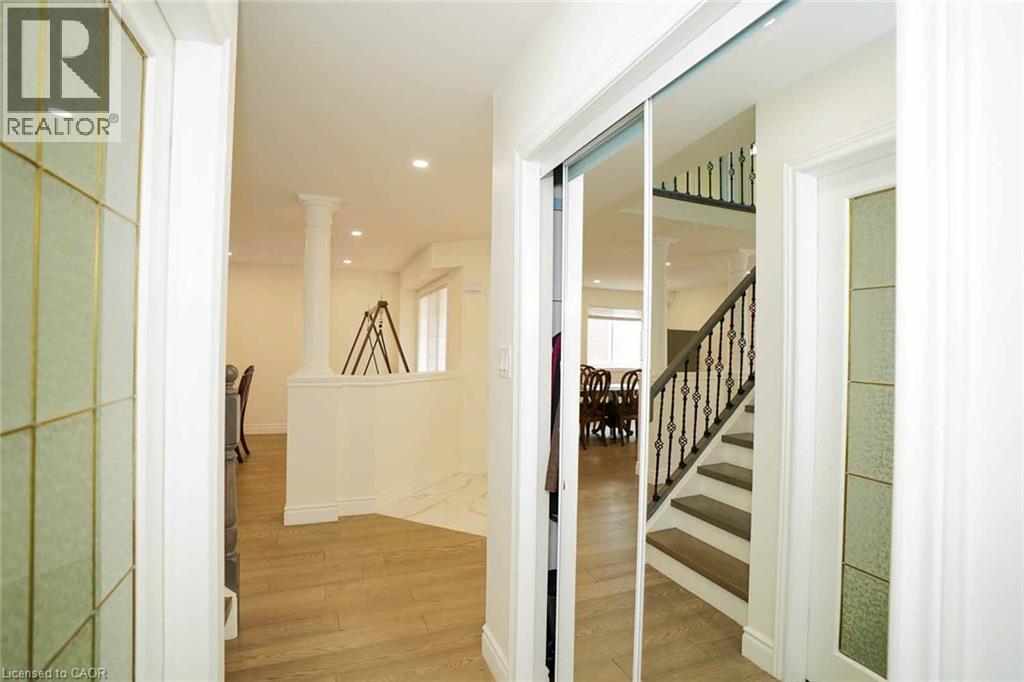 Entryway featuring mirrored closet doors, wood-finish flooring, recessed lighting, and a detailed staircase with an ornate wrought-iron railing - 187 Adler Drive, Cambridge, ON - Indoor Photo Showing Other Room