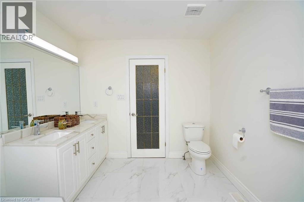 Bathroom featuring a double vanity with white cabinetry, light-colored countertops, and integrated sinks - 187 Adler Drive, Cambridge, ON - Indoor Photo Showing Bathroom
