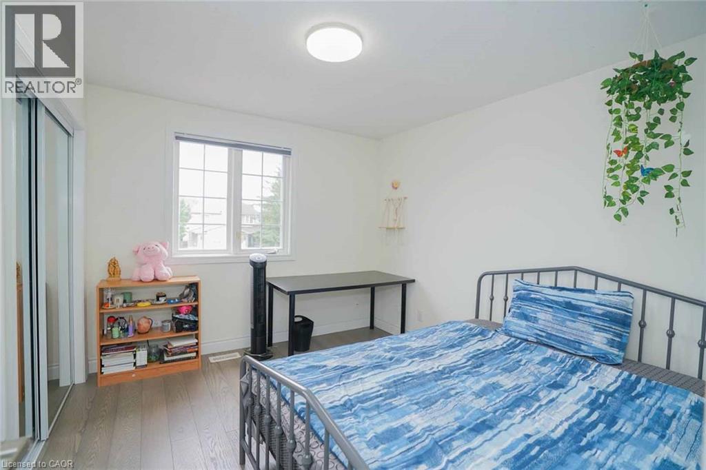 Spacious room featuring wood-finish flooring, a window with exterior views, and a sliding door closet with mirrored panels - 187 Adler Drive, Cambridge, ON - Indoor Photo Showing Bedroom