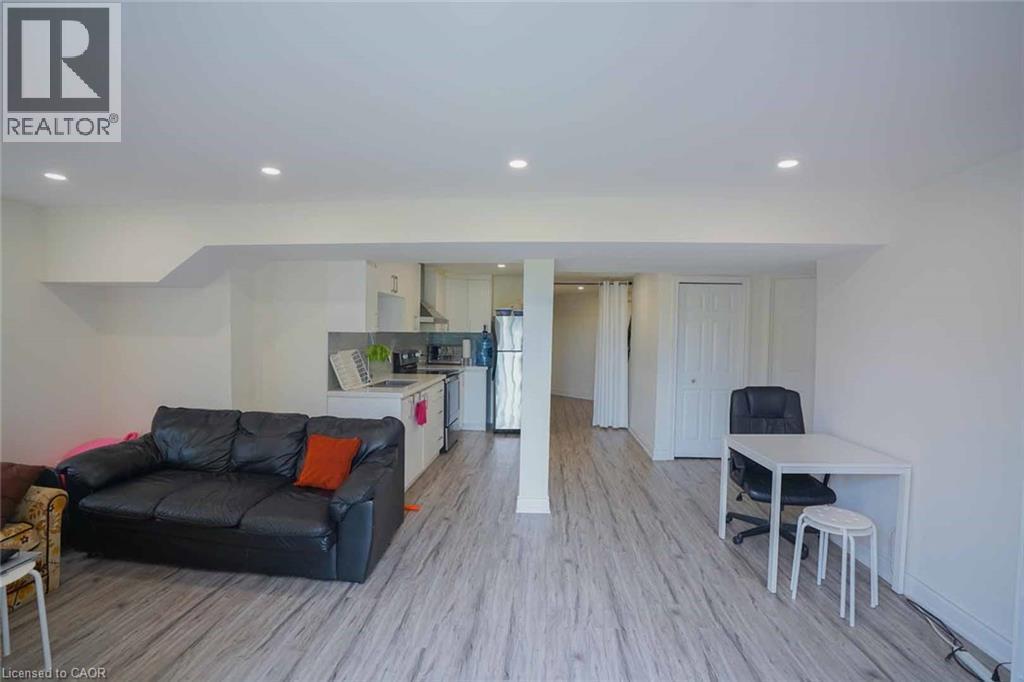 Open-concept living space featuring wood-finish flooring, recessed lighting, and a white kitchen with stainless steel appliances - 187 Adler Drive, Cambridge, ON - Indoor Photo Showing Living Room