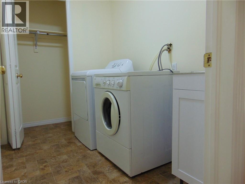 Laundry area with patterned tile flooring, built-in cabinetry, and a closet with hanging rod - 214 Snowdrop Crescent, Kitchener, ON