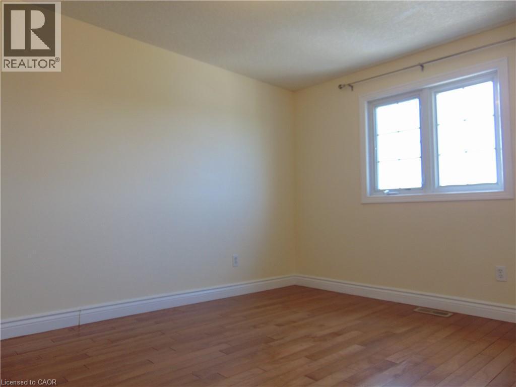 Room with light-toned walls, wood-finish flooring, white baseboards, and a double window with white trim - 214 Snowdrop Crescent, Kitchener, ON