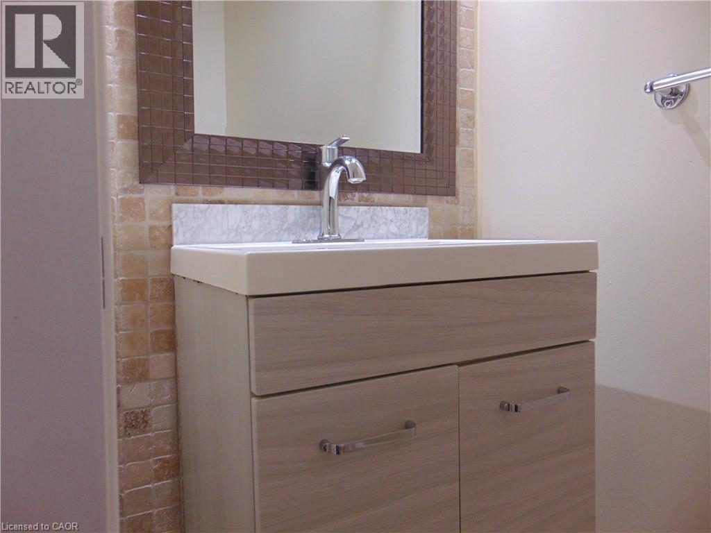 Contemporary vanity featuring light wood-finish cabinetry with polished chrome hardware, an integrated sink, and a matching backsplash - 214 Snowdrop Crescent, Kitchener, ON