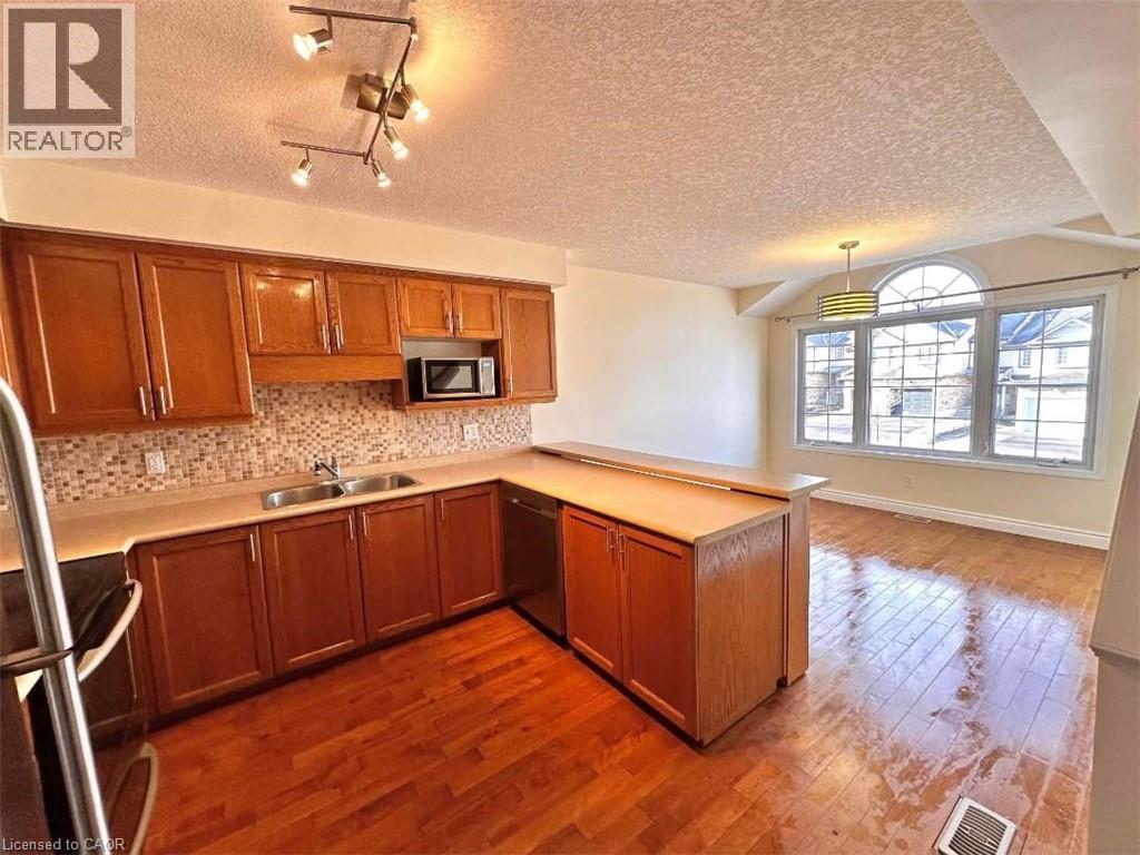 Kitchen and dining area featuring wood-finish flooring - 214 Snowdrop Crescent, Kitchener, ON - Indoor Photo Showing Kitchen With Double Sink
