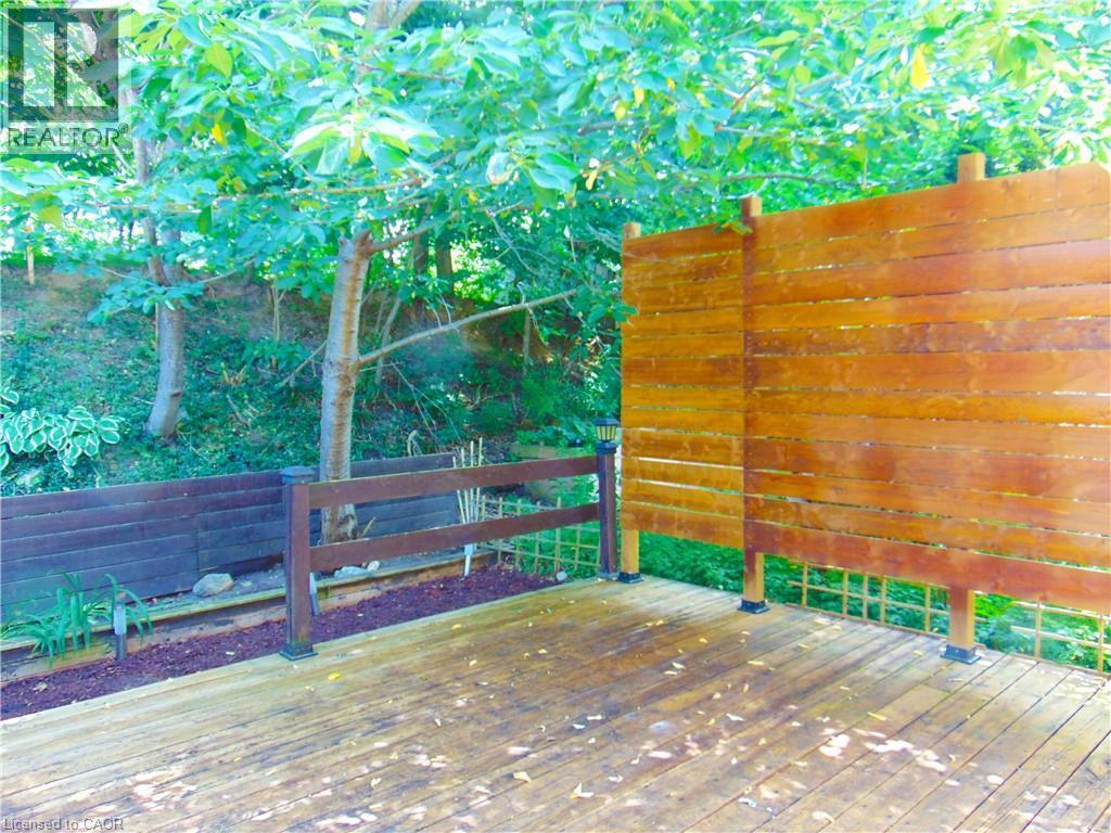 Expansive outdoor decking featuring a privacy screen, perimeter railing, and integrated landscaping with mature trees - 214 Snowdrop Crescent, Kitchener, ON
