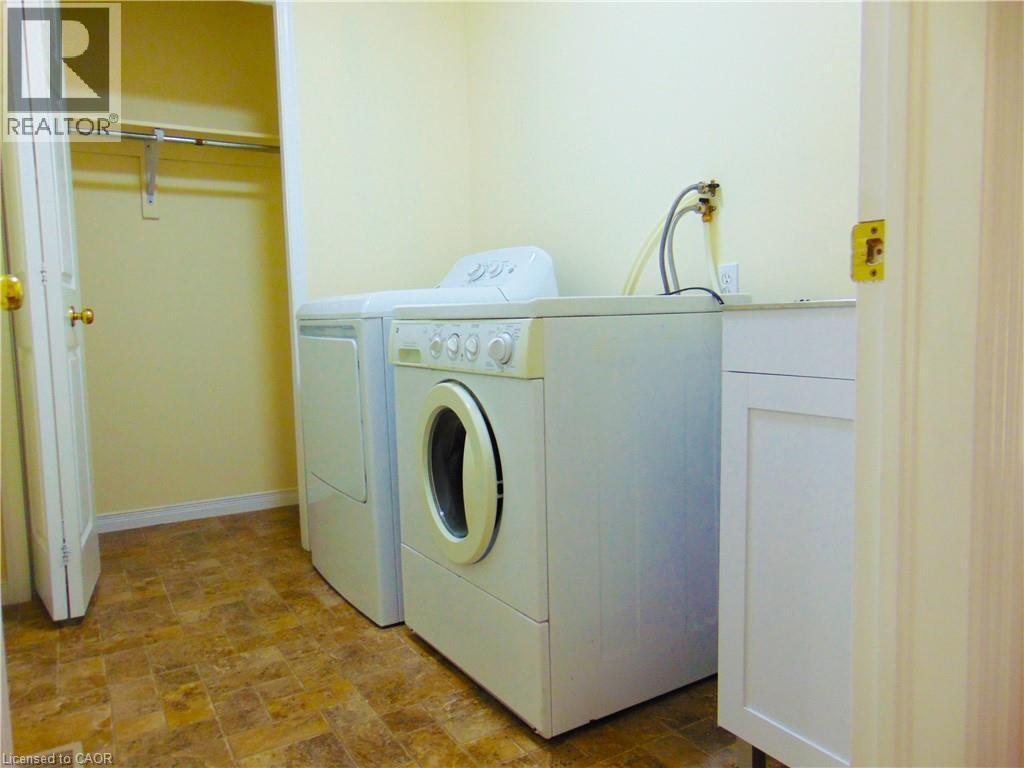 Utility area featuring a built-in cabinet with a countertop, tiled flooring, and an integrated closet with a hanging rod - 214 Snowdrop Crescent, Kitchener, ON
