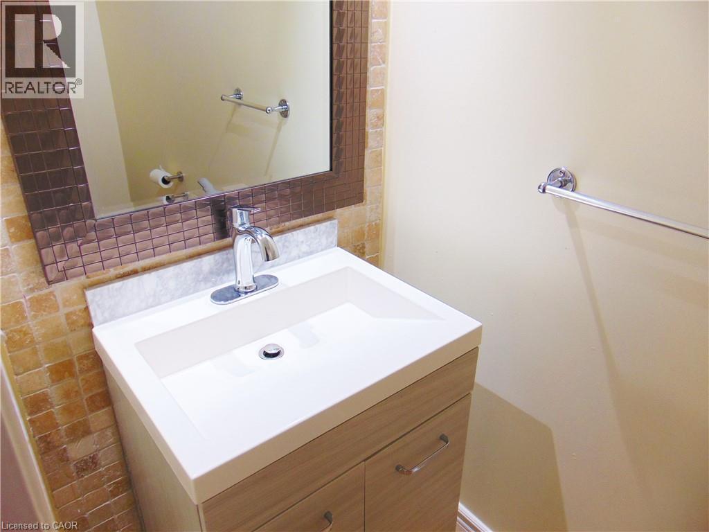 Vanity featuring a white integrated sink and countertop, wood-finish cabinetry, and chrome fixtures - 214 Snowdrop Crescent, Kitchener, ON