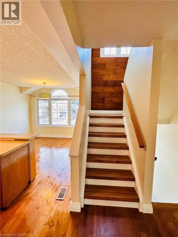 Hardwood flooring extends throughout the main level, complemented by a staircase featuring wood treads and a wood handrail - 214 Snowdrop Crescent, Kitchener, ON