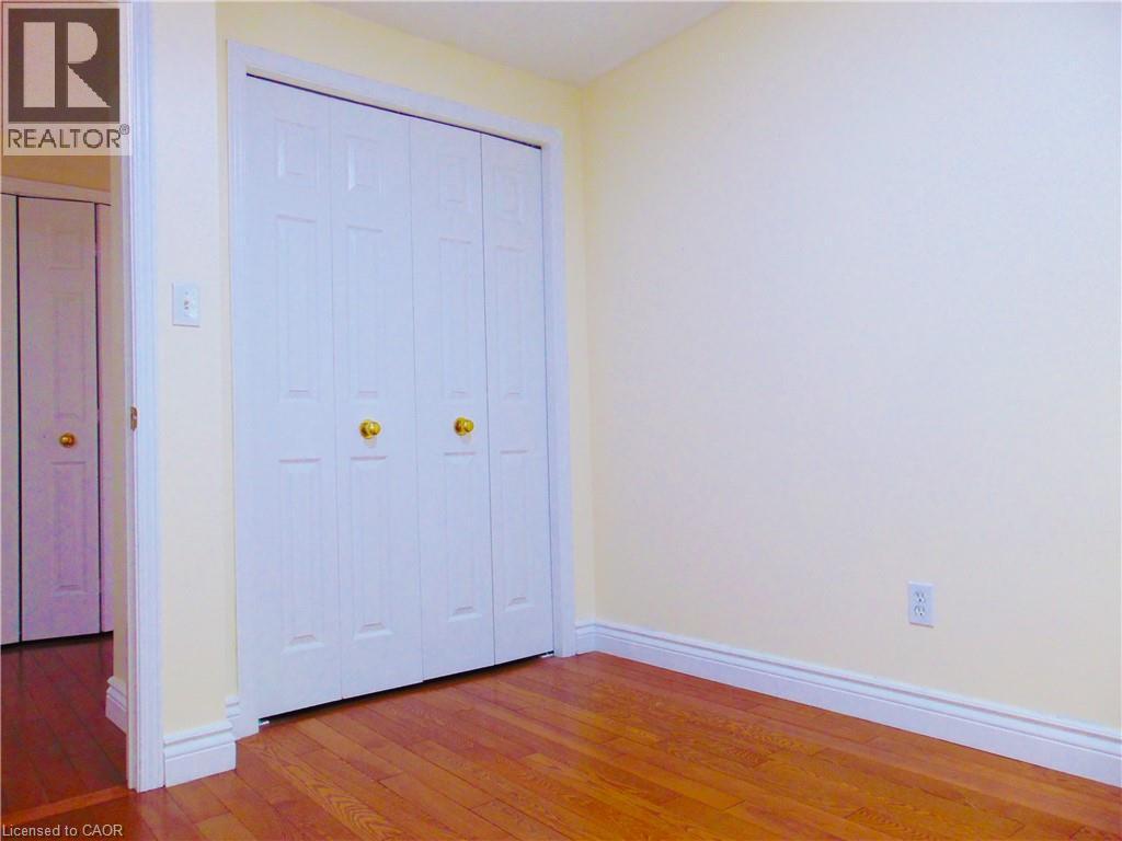 Bedroom featuring wood-finish flooring, white baseboards, and light yellow walls - 214 Snowdrop Crescent, Kitchener, ON