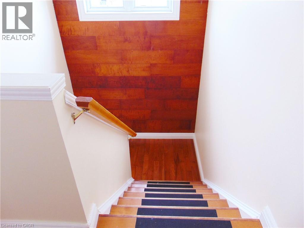 Hardwood staircase with carpeted treads, featuring a natural wood handrail and crisp white trim - 214 Snowdrop Crescent, Kitchener, ON