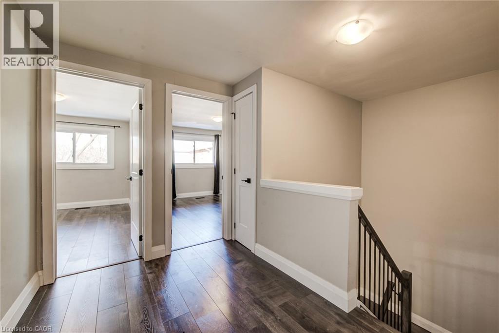 Upper level hallway featuring wood-finish flooring, light neutral wall paint, white trim, and a contemporary flush-mount ceiling light - 415-435 Garden Street Unit# 421, Cambridge, ON