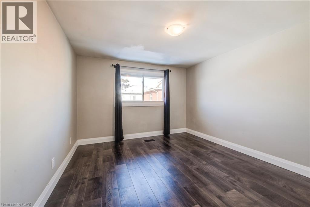 Room featuring dark wood-finish flooring, light neutral-toned walls, and white baseboards - 415-435 Garden Street Unit# 421, Cambridge, ON