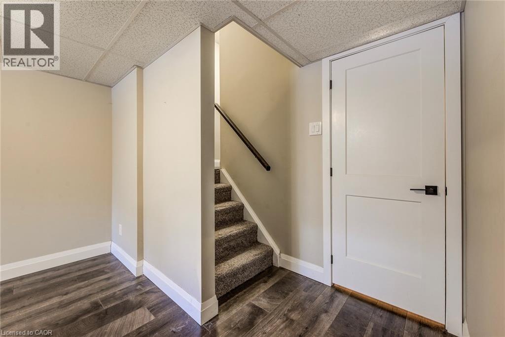 Interior space featuring wood-finish flooring, a white paneled door with matte black hardware, and an acoustic tile ceiling - 415-435 Garden Street Unit# 421, Cambridge, ON