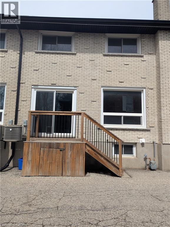 Exterior brick facade with a wooden deck featuring black metal balusters and built-in storage - 415-435 Garden Street Unit# 421, Cambridge, ON