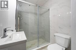 Three-piece bathroom featuring a glass-enclosed shower with sliding doors, a pedestal sink with chrome faucet, and a standard toilet -