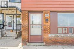 Brick facade building with a prominent front entrance featuring a storm door, an adjacent large pane window, house numbers, and a wall-mounted mailbox -