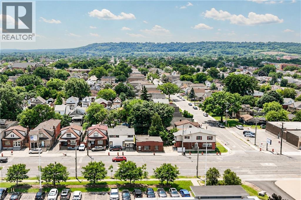 Aerial perspective highlighting a residential neighborhood with mature trees and a distant tree-covered hillside - 1274 Barton Street E, Hamilton, ON