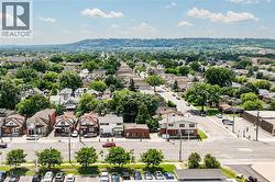 Aerial perspective highlighting a residential neighborhood with mature trees and a distant tree-covered hillside -