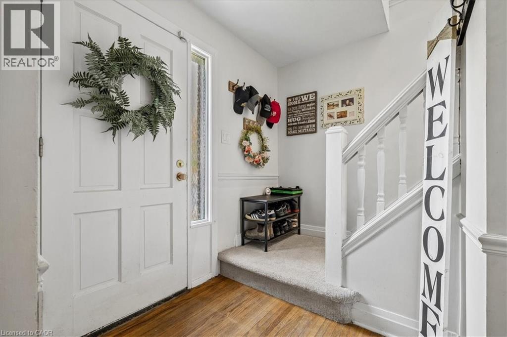 Entryway featuring a paneled door with a sidelight, wood-finish flooring, carpeted stairs with white banister, and white wall finishes - 80 Maclennan Avenue, Hamilton, ON - Indoor Photo Showing Other Room