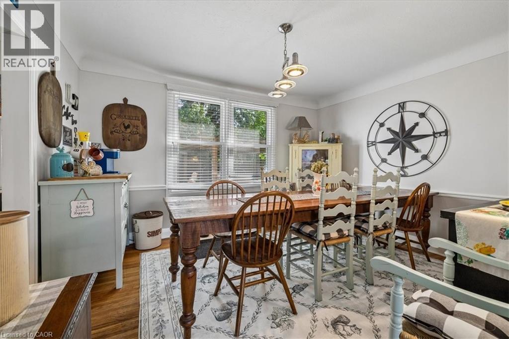 Dining area featuring wood-finish flooring, a multi-light linear pendant fixture, and a window with blinds - 80 Maclennan Avenue, Hamilton, ON - Indoor Photo Showing Dining Room
