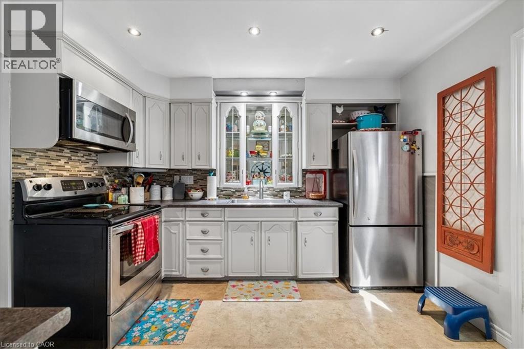 Kitchen featuring white cabinetry, stainless steel appliances, mosaic tile backsplash, recessed lighting, and wood-finish flooring - 80 Maclennan Avenue, Hamilton, ON - Indoor Photo Showing Kitchen