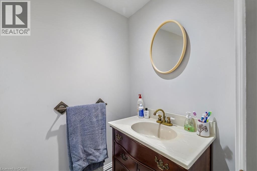 Vanity area featuring a wood-finish cabinet with brass hardware, an integrated basin, and a light-toned countertop - 80 Maclennan Avenue, Hamilton, ON - Indoor Photo Showing Bathroom