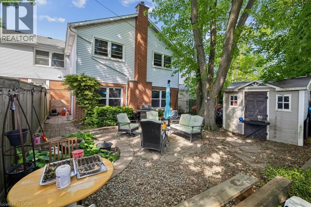 Expansive backyard featuring a stone patio, mature trees, a storage shed, and a privacy fence - 80 Maclennan Avenue, Hamilton, ON - Outdoor With Exterior