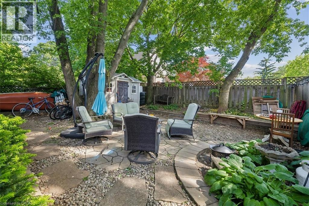 Expansive outdoor space featuring a flagstone and gravel patio, mature trees, a privacy fence, and a storage shed - 80 Maclennan Avenue, Hamilton, ON - Outdoor