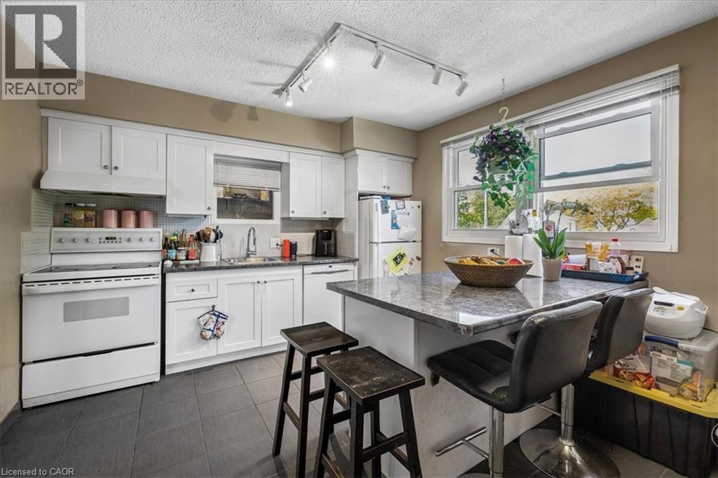 Kitchen featuring white cabinetry, dark tile flooring, a center island with a stone-finish countertop, and track lighting - 80 Maclennan Avenue, Hamilton, ON