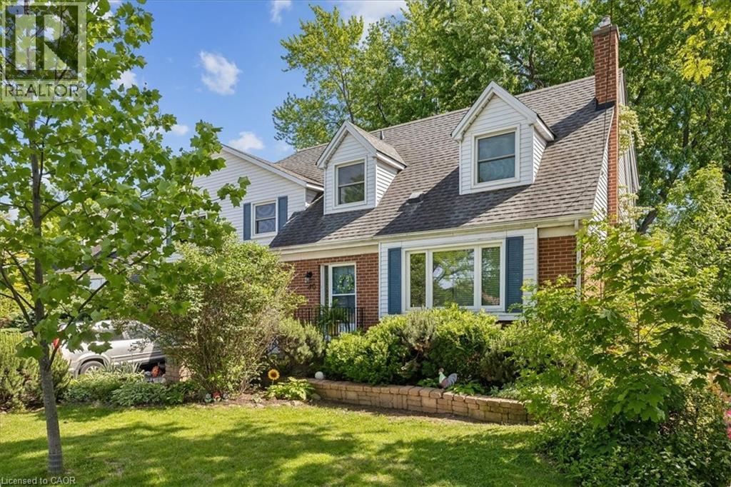 Brick and siding exterior featuring a prominent chimney, dormer windows, and blue decorative shutters - 80 Maclennan Avenue, Hamilton, ON - Outdoor