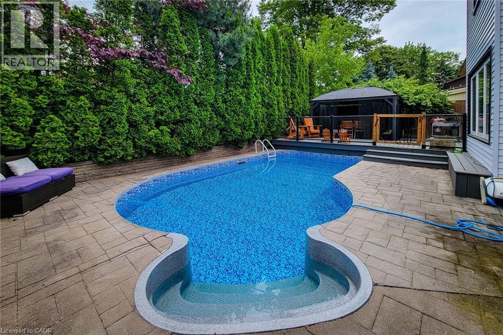 Freeform pool with integrated steps and surrounding paver patio - 29 Woodside Square, Fonthill, ON - Outdoor With In Ground Pool With Deck Patio Veranda