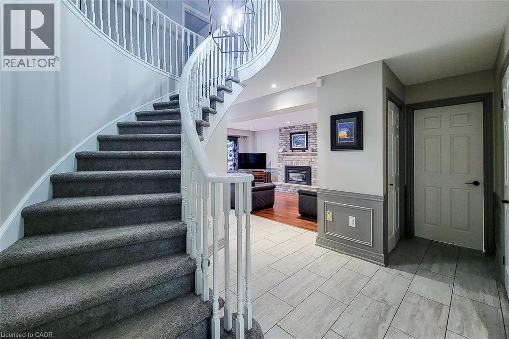 Curved staircase with carpeted treads and white wood balusters - 29 Woodside Square, Fonthill, ON - Indoor Photo Showing Other Room