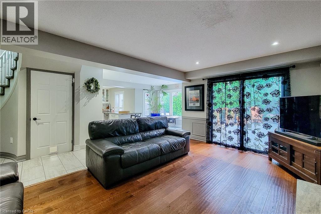 Spacious living area featuring wood-finish flooring, recessed lighting, and direct access to outdoor space via sliding glass doors - 29 Woodside Square, Fonthill, ON - Indoor Photo Showing Living Room