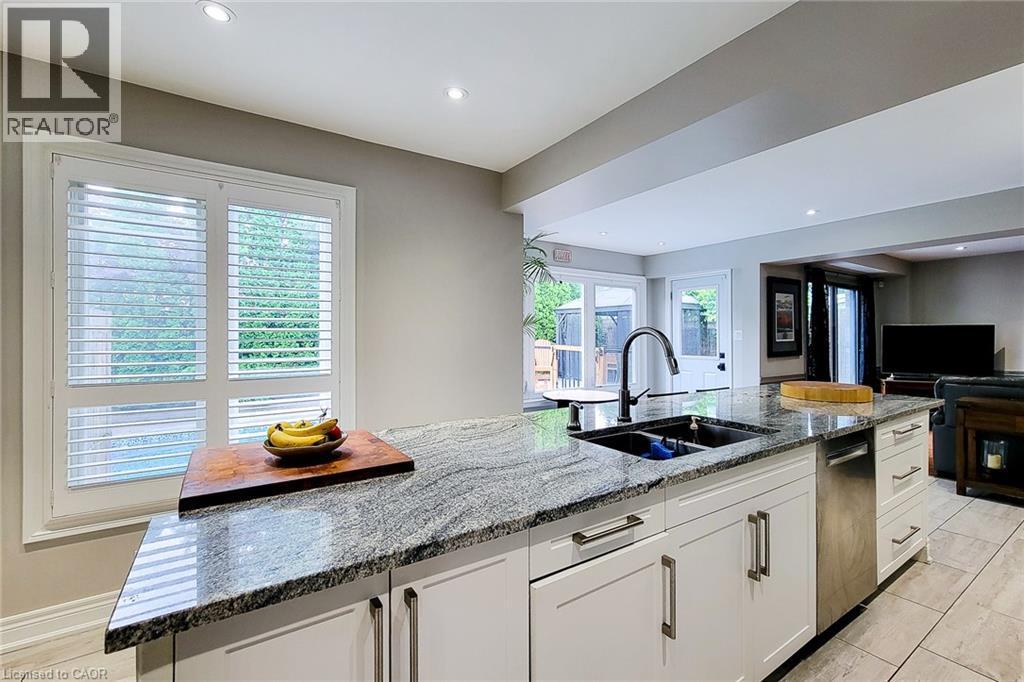 Kitchen island featuring a double basin sink, black faucet, and granite countertop - 29 Woodside Square, Fonthill, ON - Indoor Photo Showing Kitchen With Double Sink