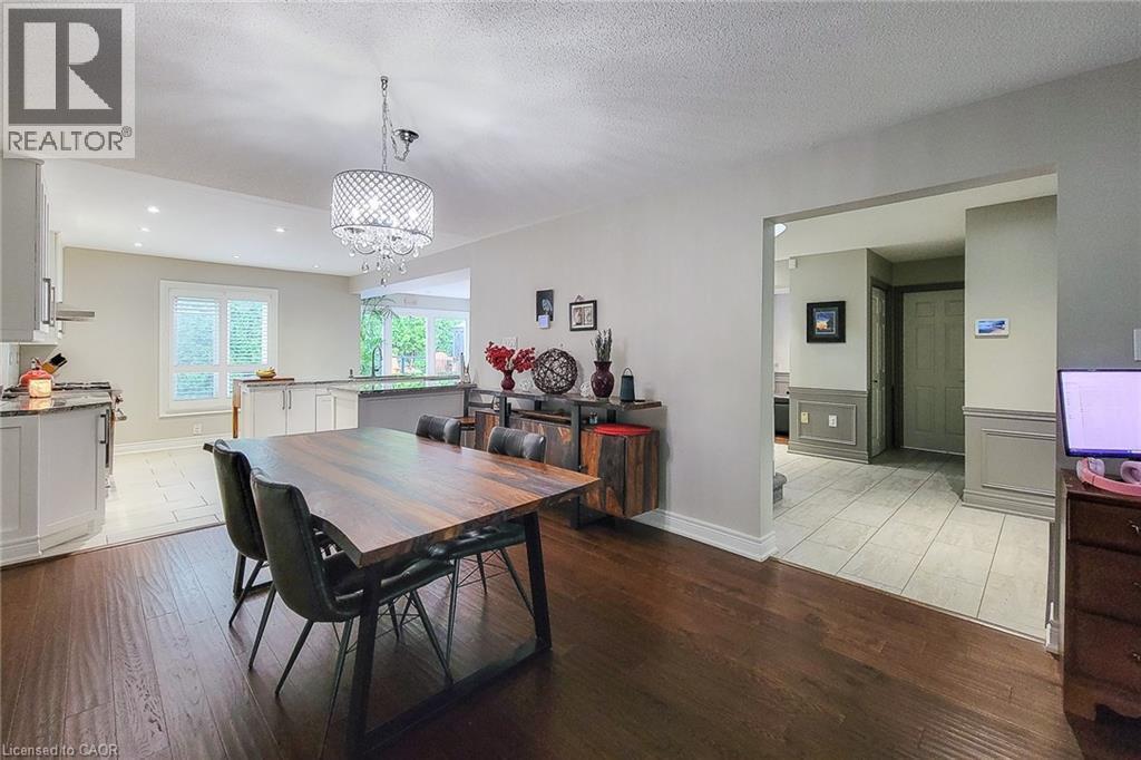 Open-concept dining area featuring dark wood-finish flooring, a tiered crystal chandelier, and an expansive archway - 29 Woodside Square, Fonthill, ON - Indoor Photo Showing Dining Room