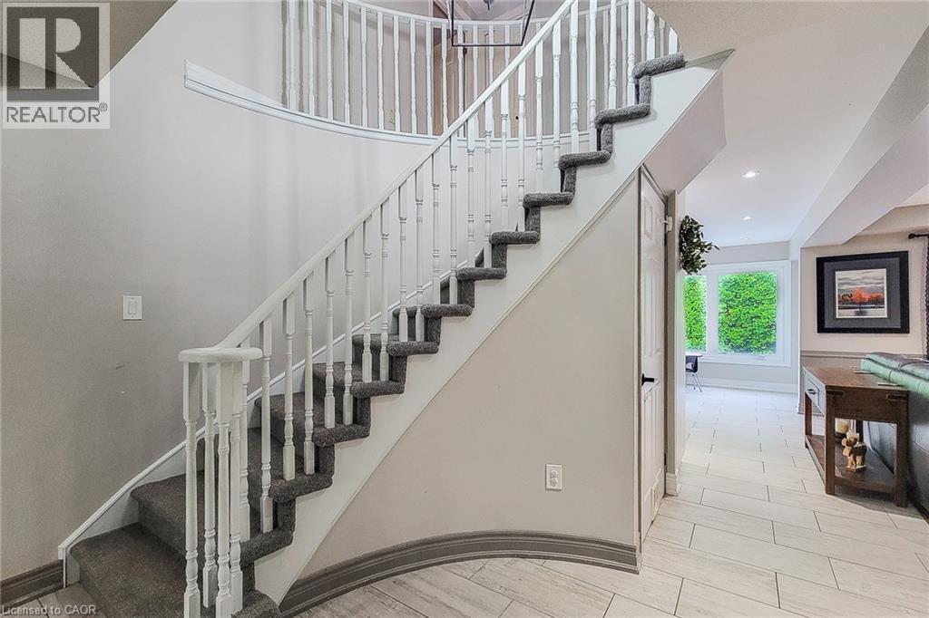 Curved staircase with white balusters and gray carpeted treads - 29 Woodside Square, Fonthill, ON - Indoor Photo Showing Other Room