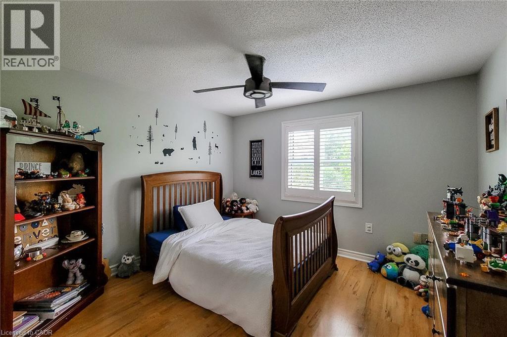 Bedroom featuring wood-finish flooring, a ceiling fan with integrated lighting, and a window with plantation shutters - 29 Woodside Square, Fonthill, ON - Indoor Photo Showing Bedroom