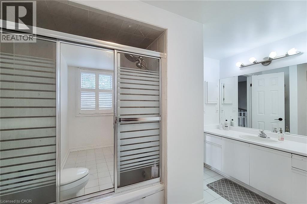 Bathroom featuring a double vanity with a large mirror, a four-light fixture, and built-in cabinetry - 29 Woodside Square, Fonthill, ON - Indoor Photo Showing Bathroom
