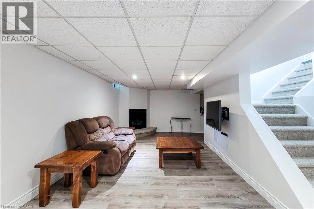 Finished basement space with wood-finish flooring, a contemporary corner fireplace, and recessed lighting - 29 Woodside Square, Fonthill, ON - Indoor