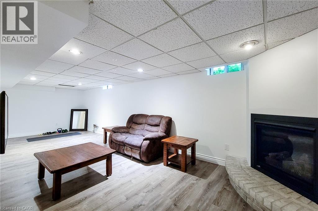 Spacious interior featuring wood-finish flooring, white walls, and a drop ceiling with recessed lighting - 29 Woodside Square, Fonthill, ON - Indoor With Fireplace
