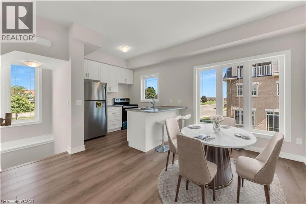 Open-concept living space featuring wood-finish flooring, a contemporary kitchen with white cabinetry, stainless steel appliances, and a peninsula with bar seating - 19 Picardy Drive Unit# 9, Hamilton, ON